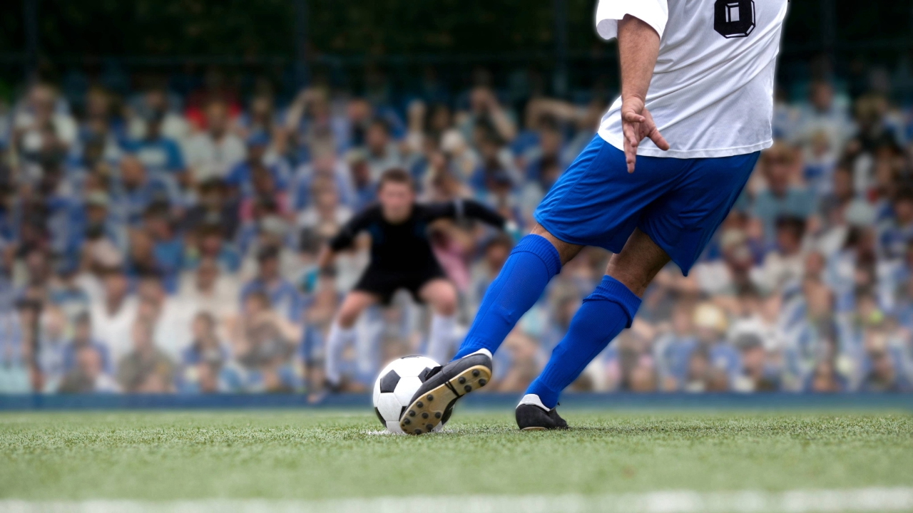 A soccer playing kicking a ball.